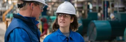 Un homme et une femme sur un chantier avec des casques blancs et des tenues bleues 